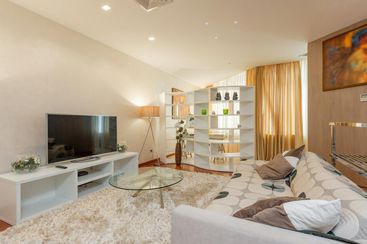 living room with painted walls, a couch with pillows, and a round glass table in front of the tv