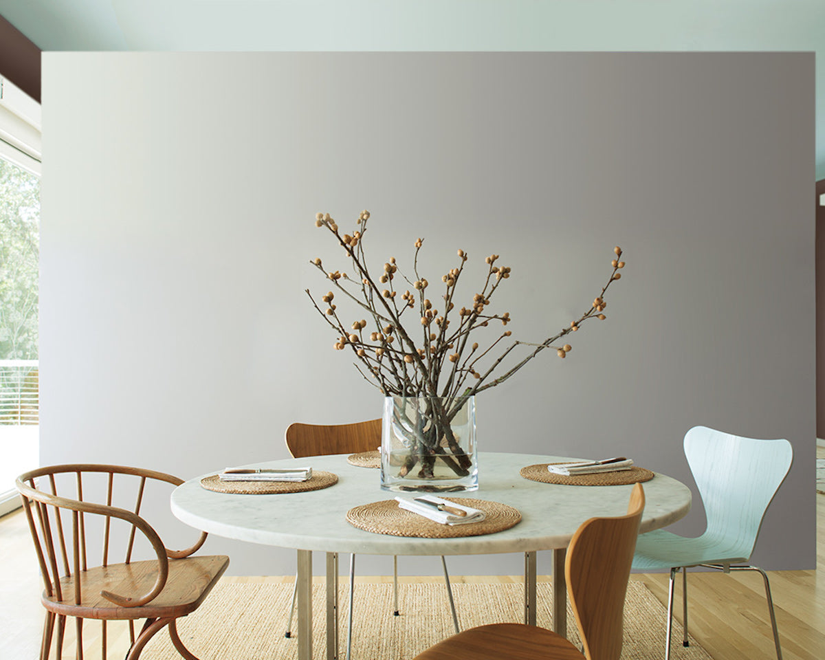 Airy kitchen with gray accent wall and mint ceiling; large paper lantern lighting above circular table with wooden chairs.